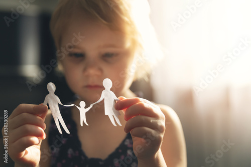 little girl with paper family in hands. concept of divorce, custody and child abuse