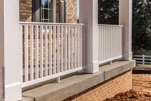 Covered porch with brick siding, pre cut and pre mitered white columns, column wraps, colonial white railing with balusters