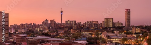 A beautiful and dramatic panoramic photograph of the Johannesburg city skyline, taken on a golden evening after sunset.