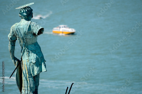 A Venetian vaporetto travels down the Guidecca Canal with a statue from the top of the San Giorgio Maggiore church in the foreground.