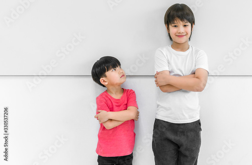 Little child boy standing arms crossed and looking face of tall child at standing arms crossed and smiling