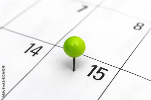 Green pinned pin in calendar on 15th day.