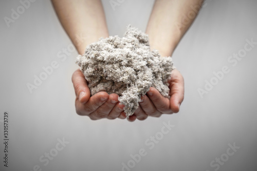 Hands holding cellulose fiber for ecological insulation of the house. Conservation of home heat and energy saving