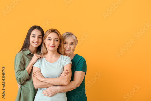 Portrait of mature woman with her adult daughter and mother on color background