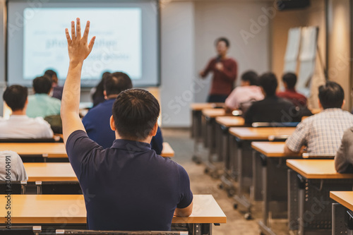 Rear view of Audience in raise hand up response for answer the question in the meeting room or conference hall over asian speaker on the stage,seminar business and education concept