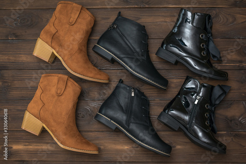 A set of three pairs of women's leather shoes on a wooden background.