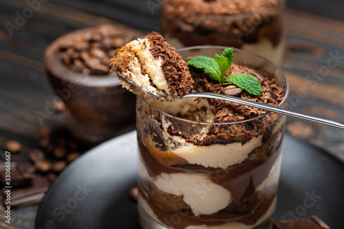 Classic tiramisu dessert in a glass cup on wooden background