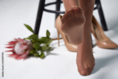 Part of woman body perfect shape legs feet skin tan wear stockings, nylons, pantyhose lingerie hosiery hose studio shot. on white background flower.