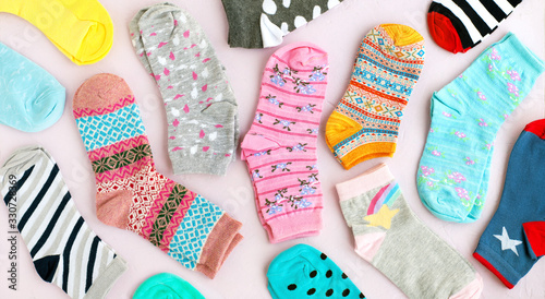 Many colorful socks in the form of a panorama. Socks of different sizes for cold seasons. Clothing for autumn and winter. Knitted socks on a pink background.