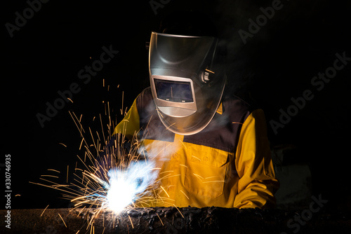 Worker welding a part of construction steel in his workshop, Welding and construction concept