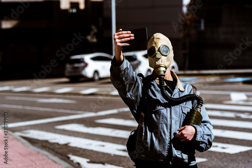 Person takes selfies with a gas mask during global epidemic. conceptual. global crisis.