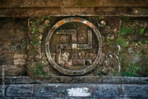 A symbol of divinity and spirituality in Hinduism and Buddhism, the ancient swastika is carved into stone on the wall of a temple in Bali, Indonesia.