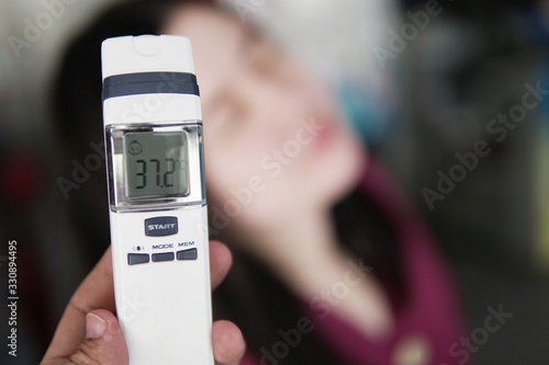 Close-up Of Hand Checking women With Digital Thermometer
