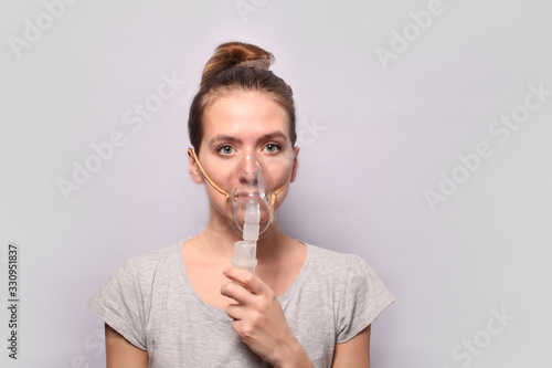 Female inhalation therapy using an inhaler mask with soft jet smoke from asthma inhaler. Inhaling the gases, they spray the drug into the lungs of the sick patient. Treatment of influenza, coronavirus