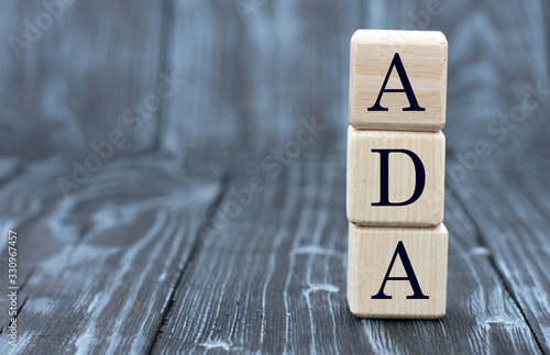 concept of the word ADA on cubes on a wooden gray background