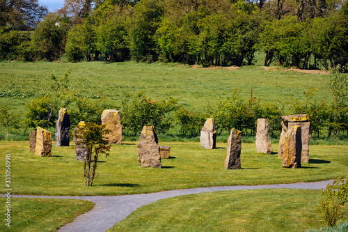 Ancient megalithic stone formation or monument on green field with forest in the background