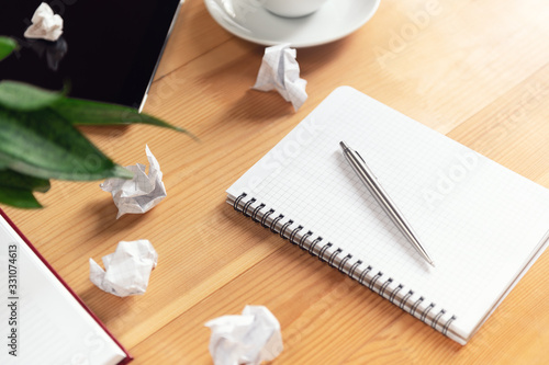 Writer workplace with notepad and pen. Crumpled papers, clear sheet in notebook on wooden table. Business planning and brainstorming. Creation process and authorship concept