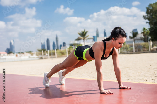Young fitness woman in sportswear doing plank exercise outdoors