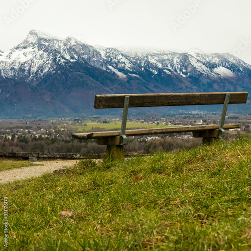 empty wooden bench on a hill with picturesque landscape scenic view on snowy Alps mountain ridge background