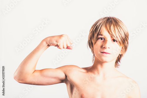 Young boy showing his biceps strength Healthy body concept Fitness teenager