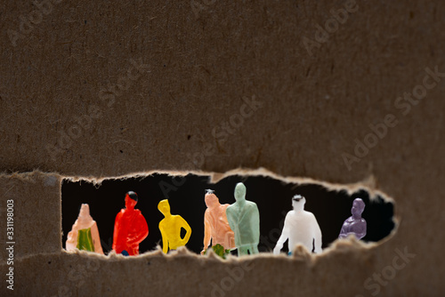 Selective focus of cardboard with hole and people figures isolated on black, concept of social equality