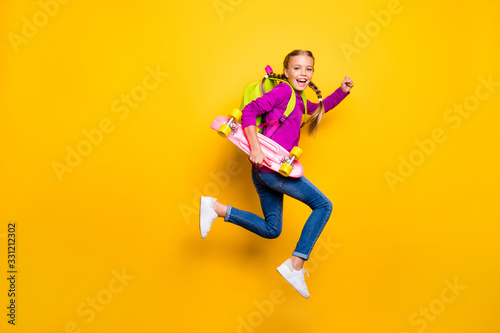 Full length body size view of her she nice attractive lovely glad cheerful cheery girl jumping running carrying skateboard isolated over bright vivid shine vibrant yellow color background