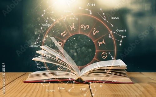 Open book on old wooden table with astrology illustration