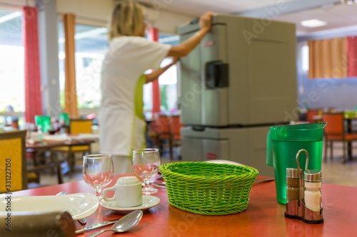 Femme agent de service en maison de retraite avec chariot repas en salle restaurant