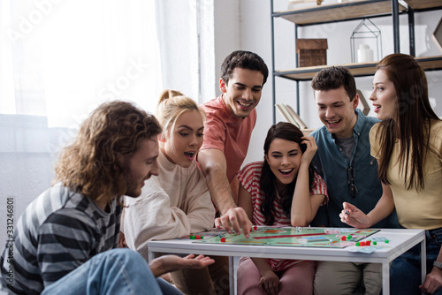 KYIV, UKRAINE - JANUARY 27, 2020: excited young friends playing monopoly game at home