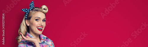 Woman holding or giving something. Excited girl in pin up cloth, showing some product or copy space for some text. Retro fashion and vintage. Red color background. Wide horizontal banner composition.