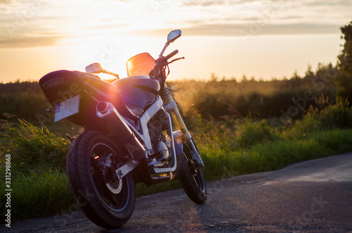 Błękitny motocykl na tle zachodzącego Słońca