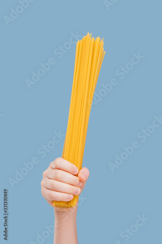 close up, child's hand held spaghetti isolated on blue background, in studio