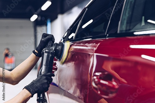 Man polishing car paint varnish in detailing studio