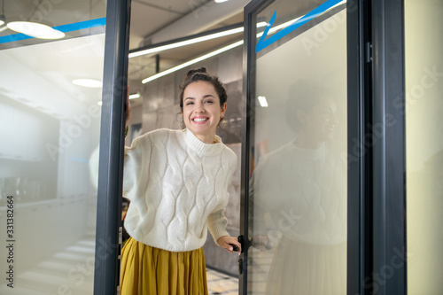 Young woman standing at the door, smiling happily