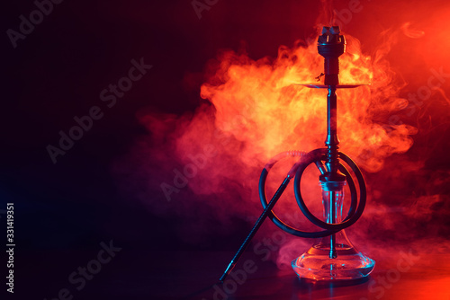 hookah shisha with glass flask and metal bowl with colored smoke on a black background