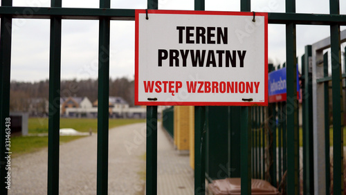 Tabliczka informacyjna, znak informacyjny na bramie wjazdowej na osiedle mieszkaniowe, napis "teren prywatny, wstęp wzbroniony". Osiedle zamknięte, strzeżone, ogrodzone.