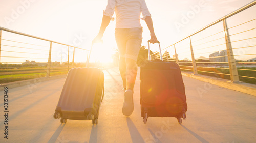 LENS FLARE: Young man in jean shorts runs with his luggage towards the sunset.