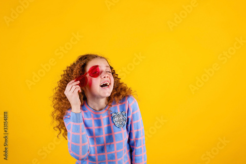 red haired , emotional girl with red glasses on a yellow background