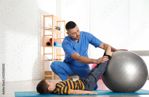 Orthopedist working with little boy in hospital gym