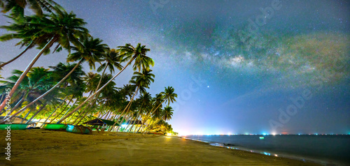 Midnight sea landscape with coconut palm tree Silhouette and Milky Way in the sky on a beautiful summer night. Long exposure photograph.