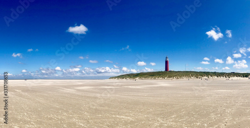 lighthouse at the beach against blue sky. panoramic picture / panorama of texel lighthouse on a sunny day in summer.