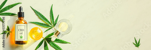 Glass brown bottle with cannabis CBD oil with label and hemp leaves on a marble background. Copy space