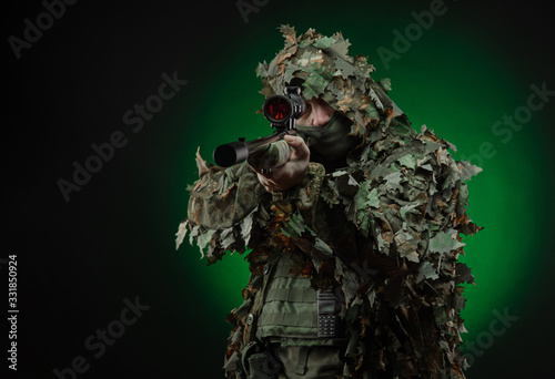 sniper in a poncho camouflage suit and a sniper rifle