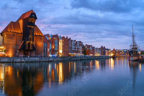 Panoramic view of the Medieval Crane and other old buildings along waterfront at the Main Town in Gdansk in the evening.