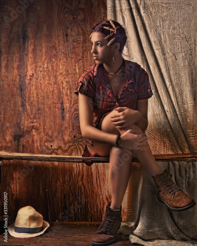 Joven campesina Santana con fondo de madera con decoración de pelillos de tender y en pose tranquila y sexy con camisa a cuadros carmelita