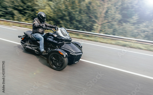 Unknown motorbiker riding three wheels motorbike along mountain road