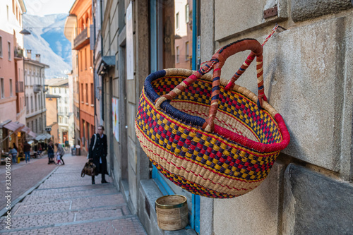 LUGANO, SWITZERLAND - MARCH 7, 2020: A colored wicker shopping basket hanging on the wall of a house in one of the streets in Lugano