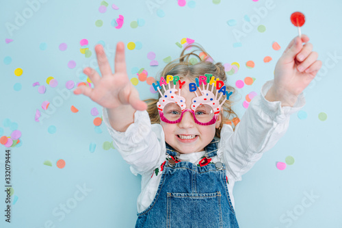 Cheerful little birthday girl lies on a floor, her hands extended up