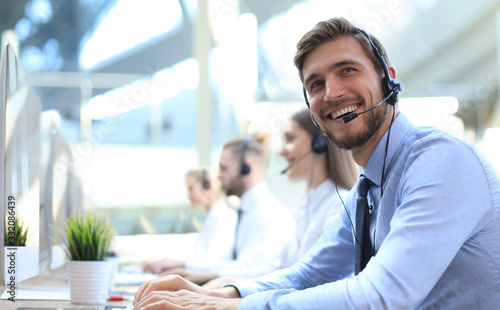 Portrait of call center worker accompanied by his team. Smiling customer support operator at work.