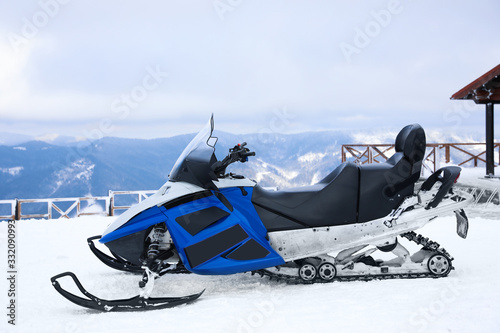 Modern snowmobile on hill at mountain ski resort